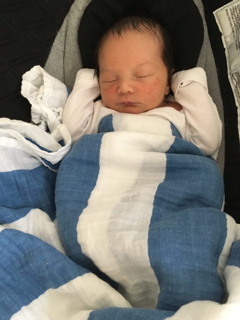 JD right after Cat and her husband brought him home. Picture of JD sleeping bundled in a white and blue blanket.